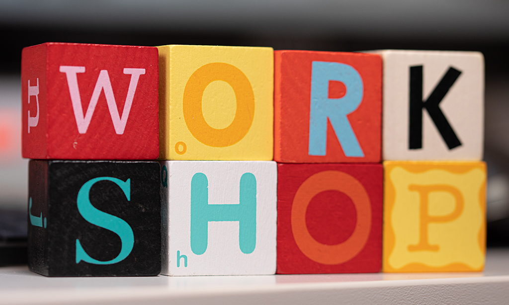 Auf bunten Holzklötzchen stehen Buchstaben und die Klötzchen sind zum Wort „Workshop“ zusammengestellt. 