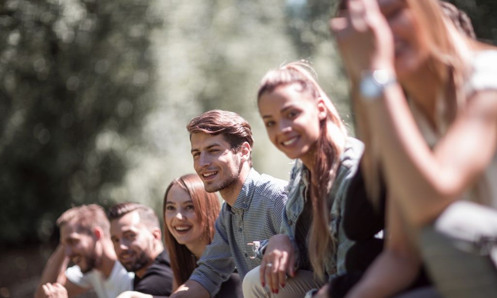 Eine Gruppe junger Menschen sitzt in der Natur.