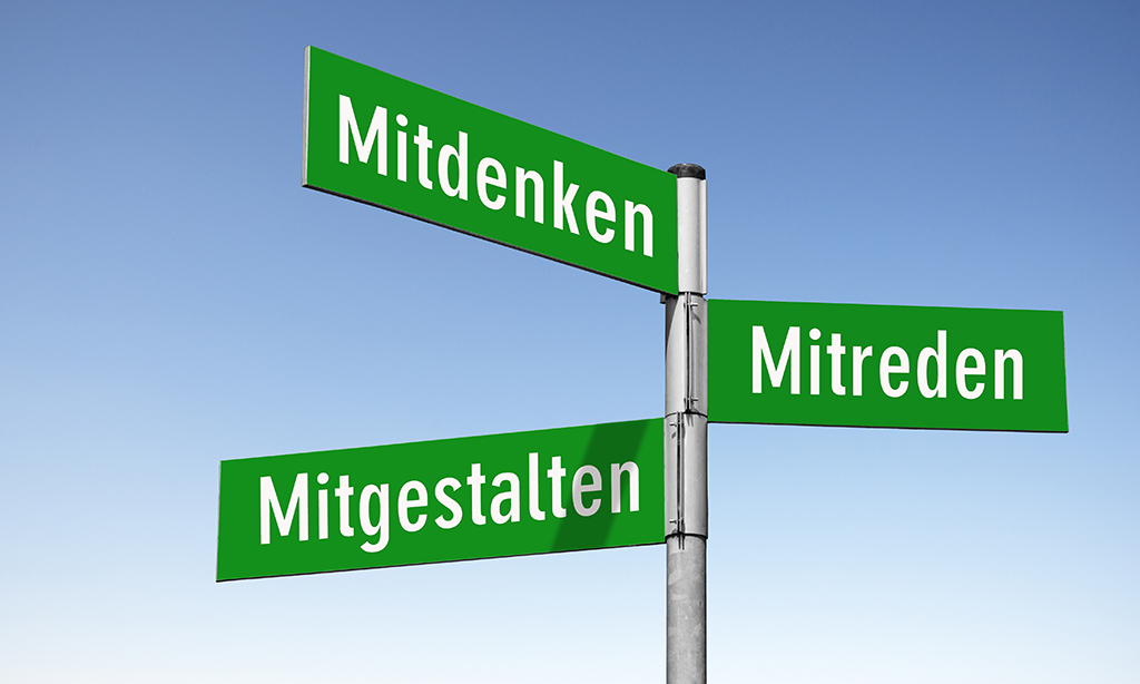 Grüner Wegweiser mit den Richtungsweisungen „Mitdenken, Mitreden und Mitgestalten“