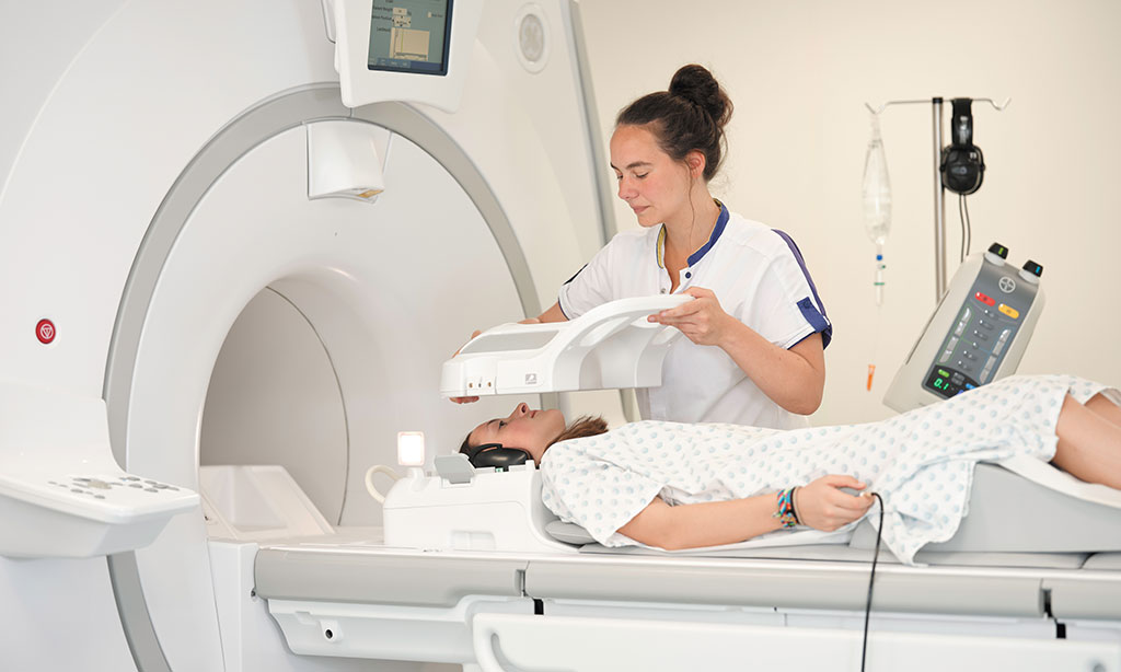 Ein Mädchen wird von einer Krankenschwester in einen Kernspintomographen gefahren.