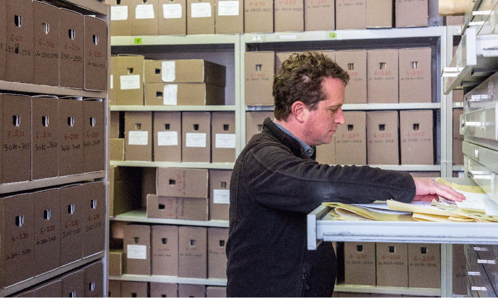Ein Mann durchsucht einen geöffneten Aktenschrank.