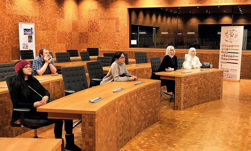 Vier Frauen und ein Mann sitzen im Parlament und lauschen einem Vortrag.