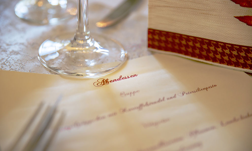 Menükarte liegt auf eingedecktem Restauranttisch.