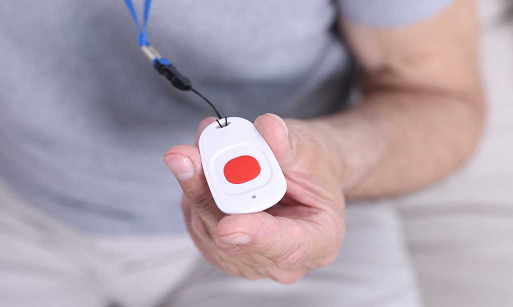 Eine alte Person hält einen weißen Notrufsender in der Hand