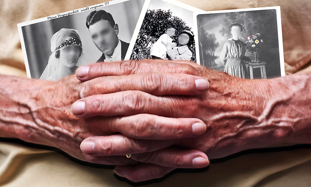 Zwei Hände halten Schwarz-Weiß-Fotos auf denen die Gesichter der Personen verschwommen sind.