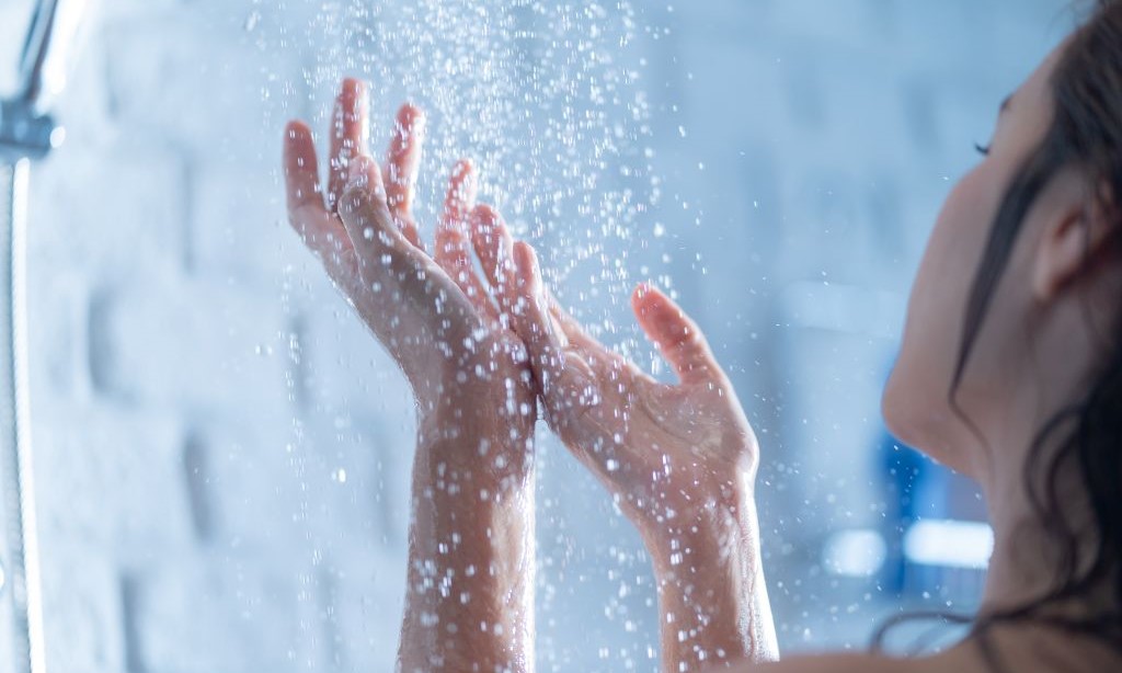 Eine Frau steht unter der Dusche.