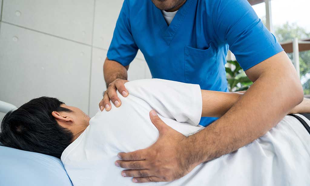 Ein Krankenpfleger hilft einer Person aus dem Bett.
