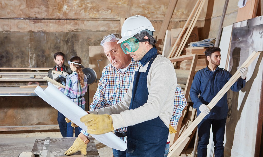 Schreiner und Lehrlinge mit Bauplan