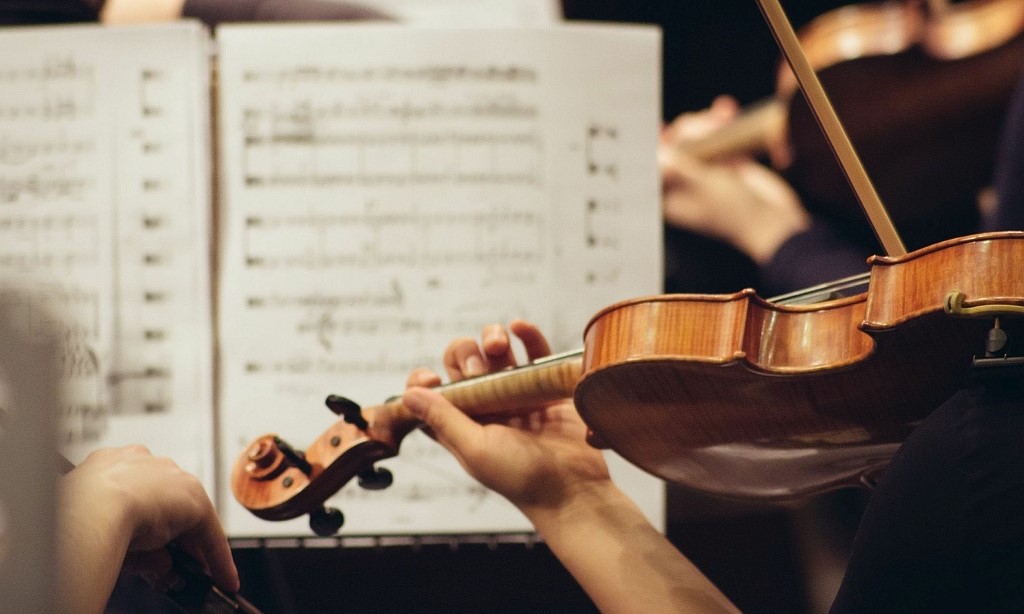 Eine Frau spiel Violine in einem Orchester. Vor ihr eine Partitur.