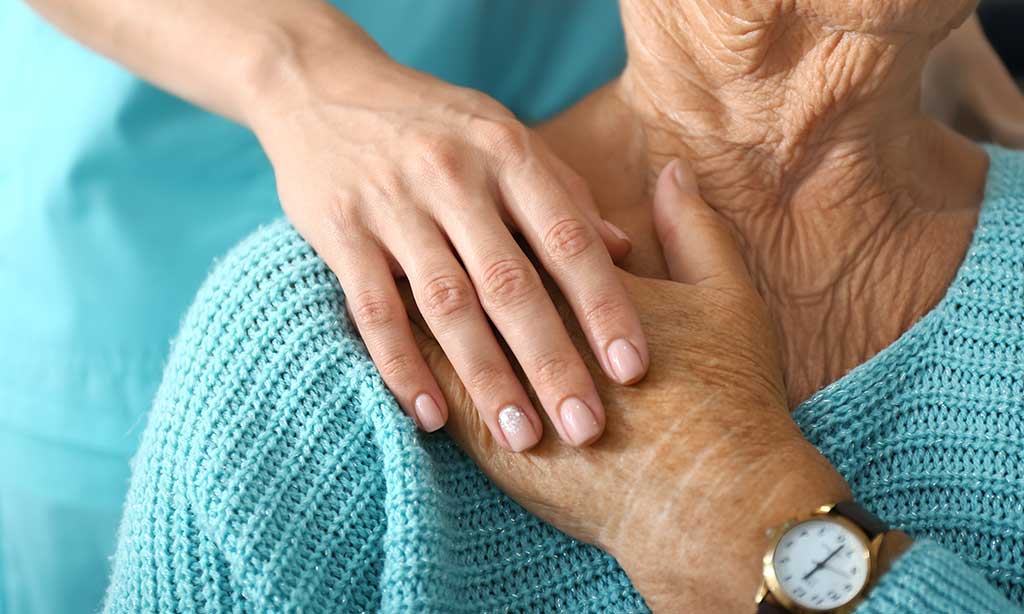 Eine alte Frau hält die Hand einer jungen Frau, die hinter ihr steht.