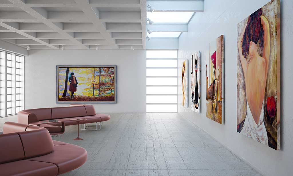In einer Kunstgalerie hängen verschiedenen Gemälde an den Wänden. Ein Sofa steht davor und der Raum wird durch viele Fenster lichtdurchflutet. 