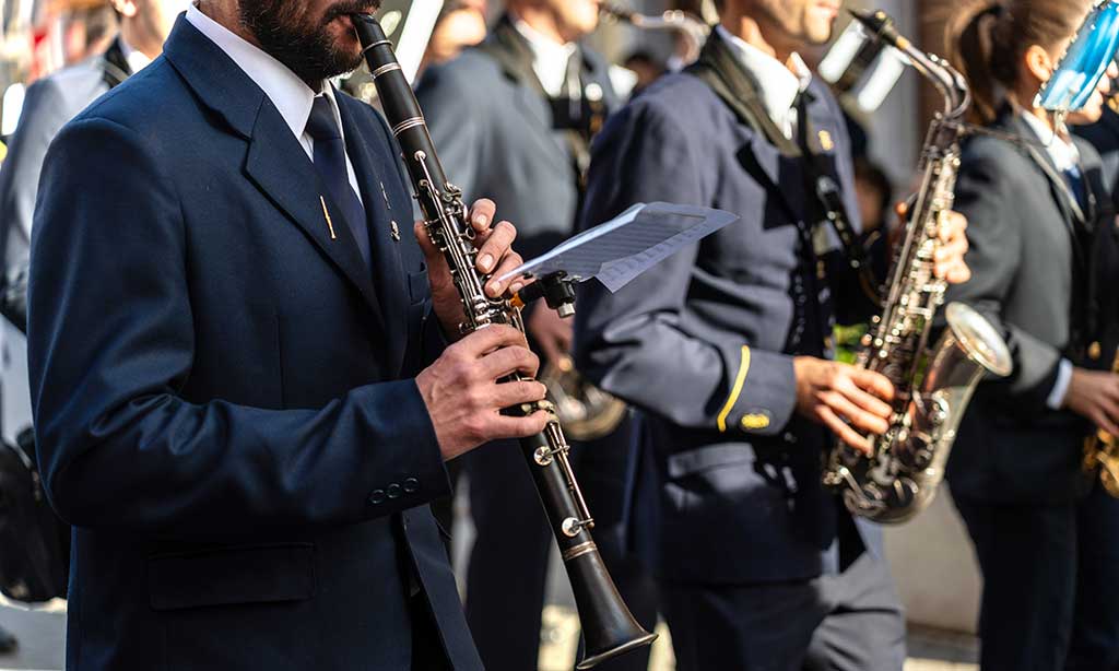 Ein Musikverein in Uniform zieht durch die Straße und musiziert auf Blasinstrumenten