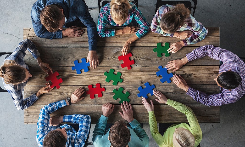 Menschen sitzen am Tisch und puzzeln.