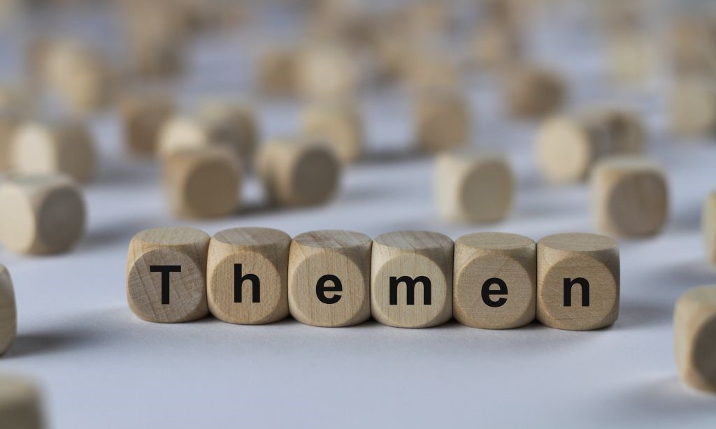 Holzwürfel mit Buchstaben sind zum Wort „Themen“ gruppiert.