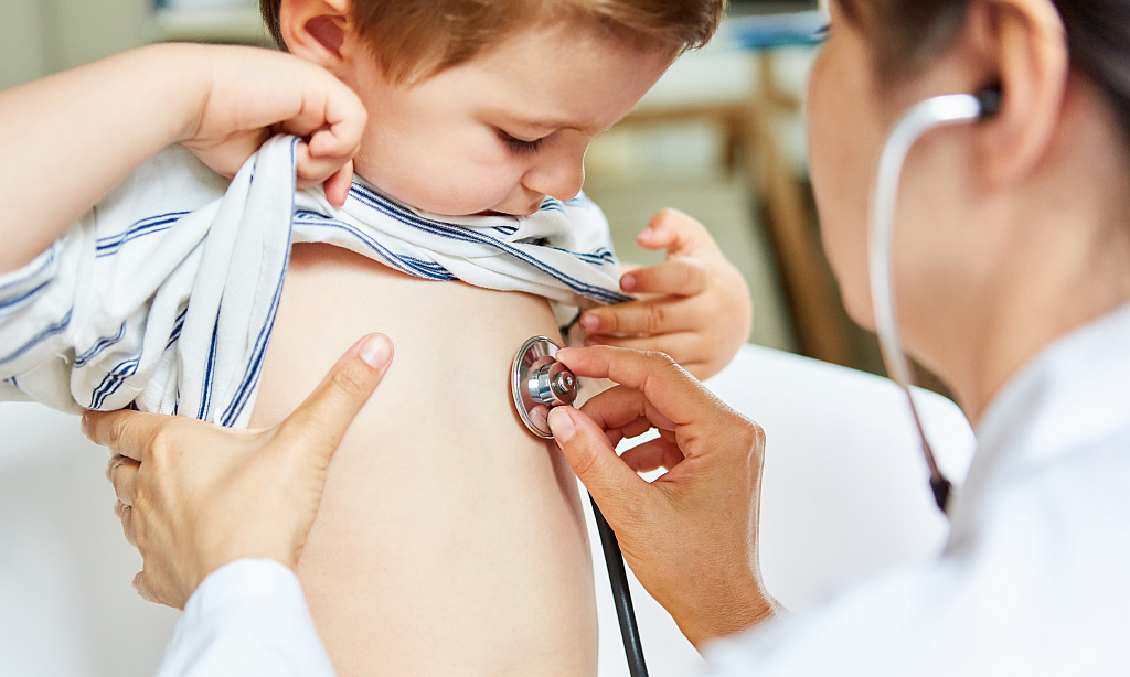 Kinderärztin beim Abhören von Lunge mit Stethoskop