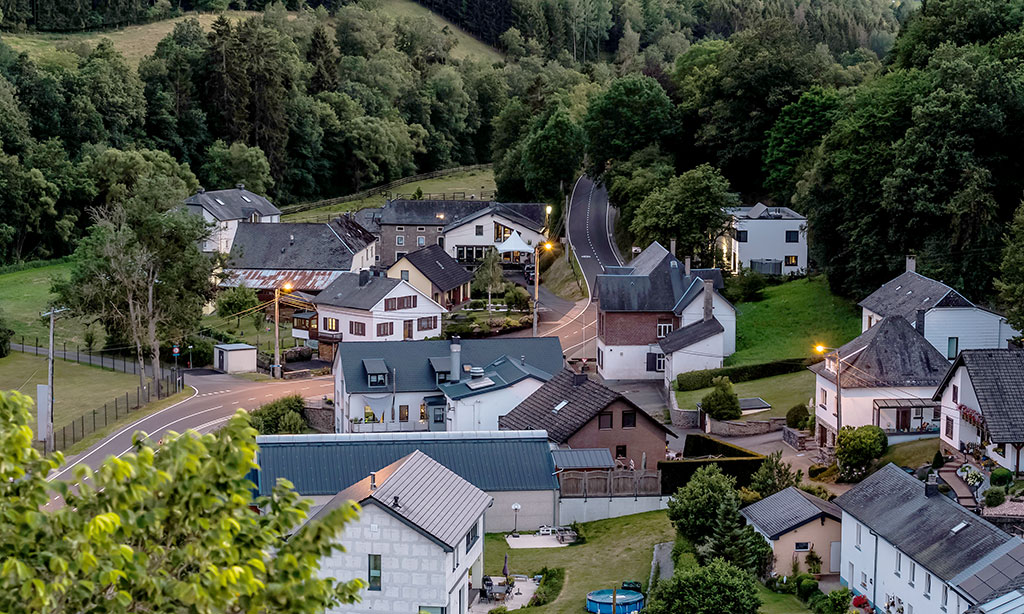 Luftaufnahme einer Häusergruppe in Burg Reuland gesäumt von Bäumen.