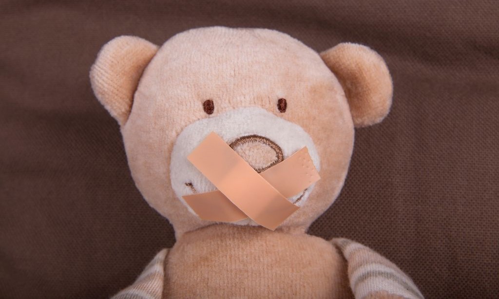 Teddybär mit überkreuzt geklebten Pflastern auf dem Mund