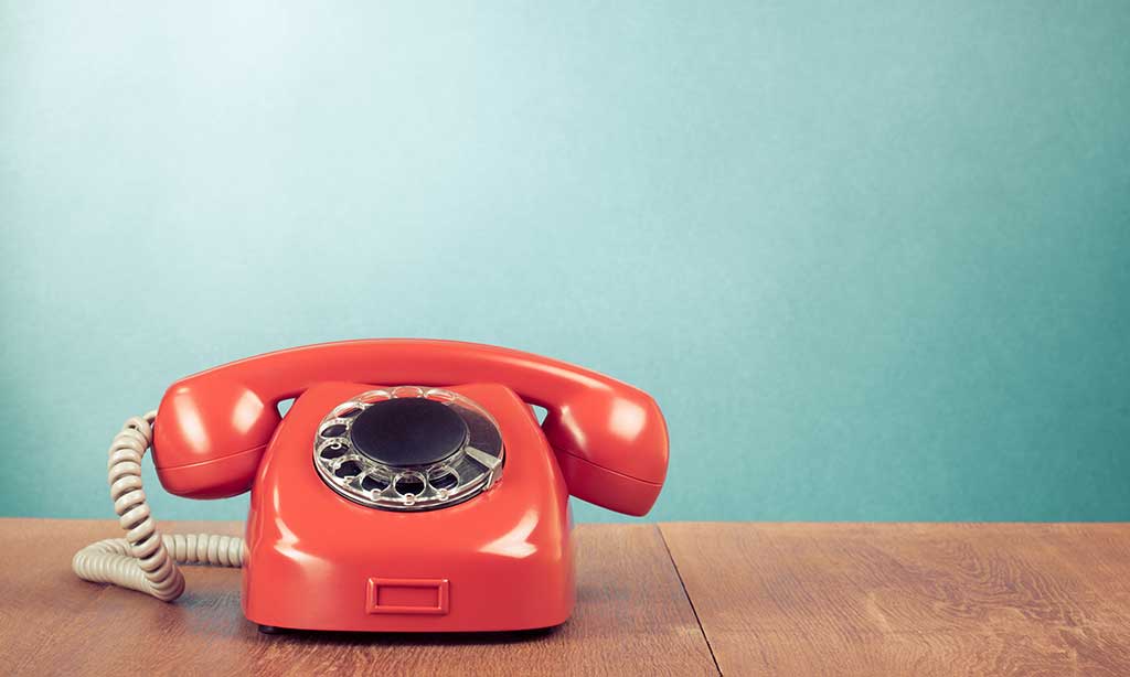 Ein rotes Telefon steht auf einem Holztisch