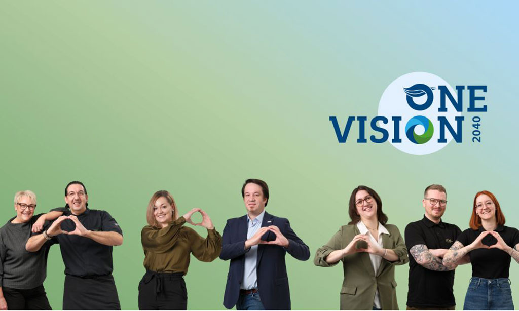 Männer und Frauen aus einem Team stehen unter dem Logo der Tourismussstrategie „One Vision 2040“.