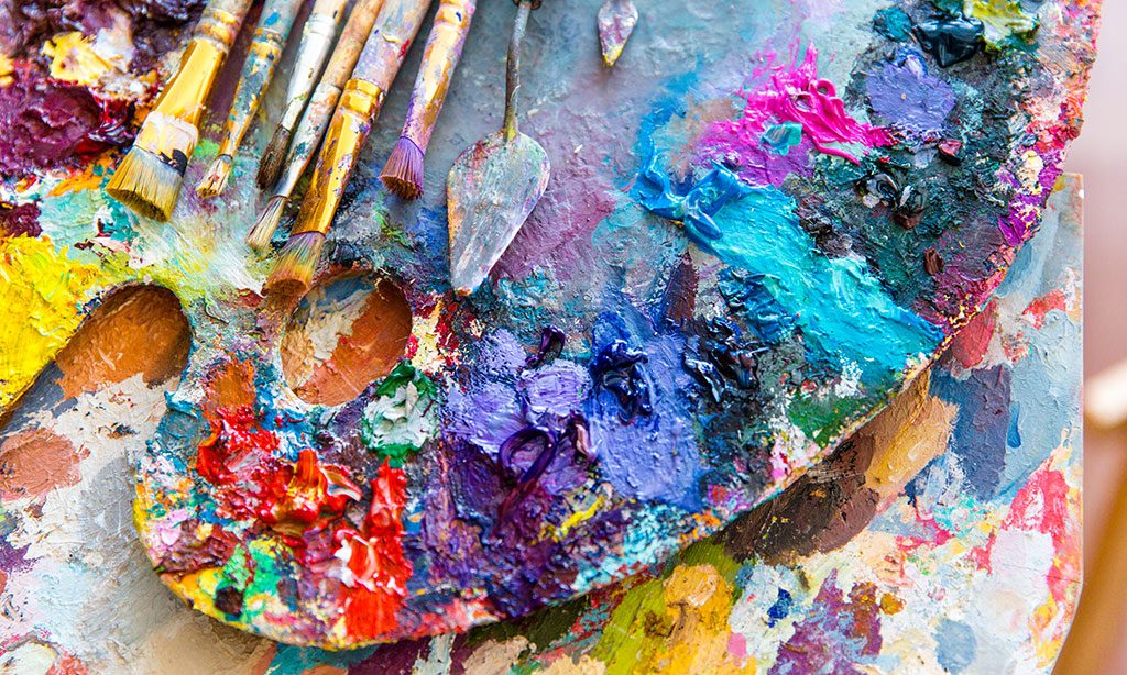 Eine Palette mit bunt gemischten Farben und Pinseln. 