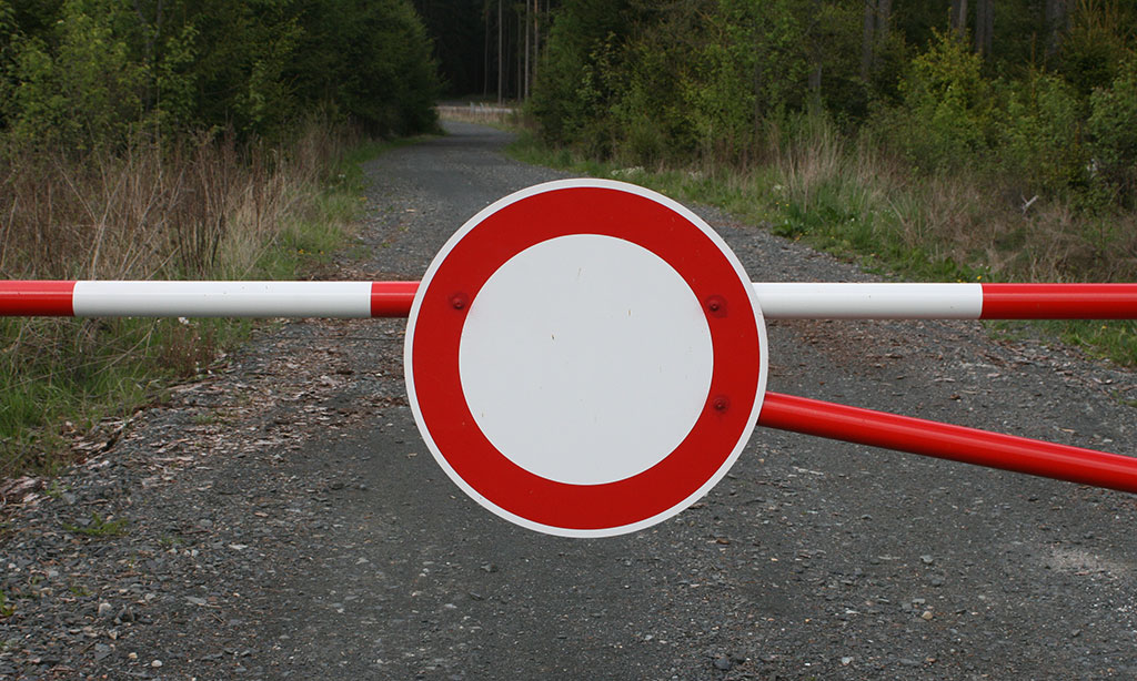 Schlagbaum mit Verbotsschild im Wald.